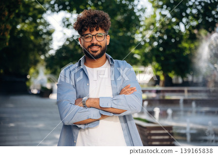 Arms crossed, standing. Handsome man is outdoors in the city Arms crossed, standing. Handsome man is outdoors in the city 139165838
