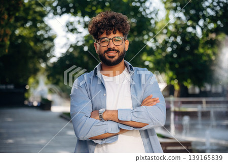 Arms crossed, standing. Handsome man is outdoors in the city 139165839
