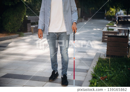 In casual clothes. A blind man with white cane is in the city In casual clothes. A blind man with white cane is in the city 139165862