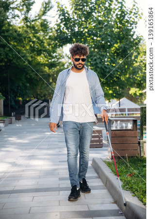 Having a walk, using cane stick. Blind man with white cane and sunglasses is in the city Having a walk, using cane stick. Blind man with white cane and sunglasses is in the city 139165864