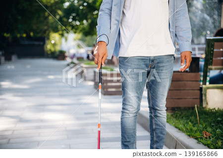 In casual clothes. A blind man with white cane is in the city In casual clothes. A blind man with white cane is in the city 139165866
