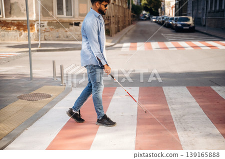 Crossing the road. Blind man with white cane and sunglasses is in the city Crossing the road. Blind man with white cane and sunglasses is in the city 139165888