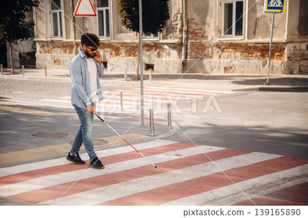 Crossing the road. Blind man with white cane and sunglasses is in the city Crossing the road. Blind man with white cane and sunglasses is in the city 139165890