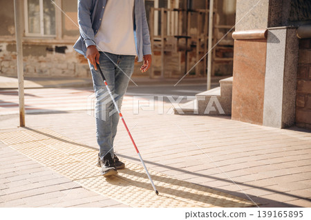Walking on the pavement. A blind man with white cane is in the city 139165895