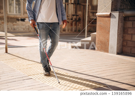 Walking on the pavement. A blind man with white cane is in the city Walking on the pavement. A blind man with white cane is in the city 139165896