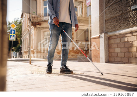 Walking on the pavement. A blind man with white cane is in the city Walking on the pavement. A blind man with white cane is in the city 139165897