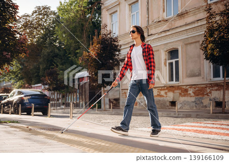 Road crossing. Blind young guy is in the town outdoors Road crossing. Blind young guy is in the town outdoors 139166109