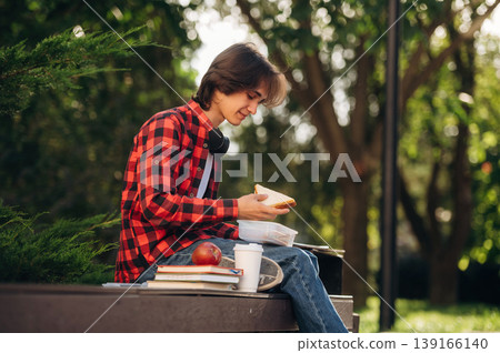 Time for lunch, with food. Male student is in the public park outdoors Time for lunch, with food. Male student is in the public park outdoors 139166140