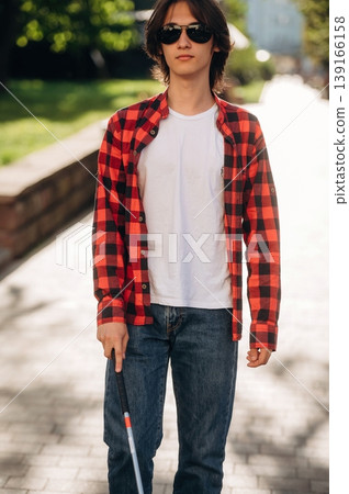 White cane is in hand. Blind young guy is in the town outdoors White cane is in hand. Blind young guy is in the town outdoors 139166158