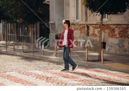 Road crossing. Blind young guy is in the town outdoors Road crossing. Blind young guy is in the town outdoors 139166165