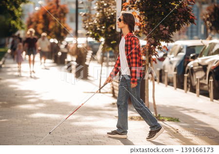 The practical use of white cane. Blind young guy is in the town outdoors The practical use of white cane. Blind young guy is in the town outdoors 139166173