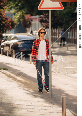 Blind young guy is in the town outdoors Blind young guy is in the town outdoors 139166177