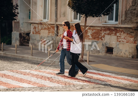 Woman is helping blind guy cross the road Woman is helping blind guy cross the road 139166180
