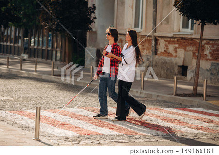 Woman is helping blind guy cross the road Woman is helping blind guy cross the road 139166181