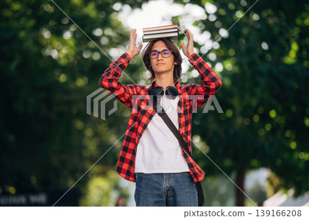 Having fun, holding books on the head. Young student is having a walk in the town Having fun, holding books on the head. Young student is having a walk in the town 139166208