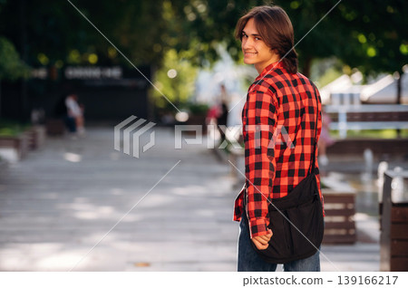 In red checkered shirt. Young student is having a walk in the town In red checkered shirt. Young student is having a walk in the town 139166217
