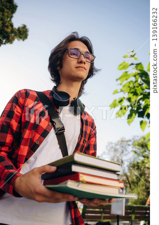 Many of the books in hands. Young student is having a walk in the town Many of the books in hands. Young student is having a walk in the town 139166232
