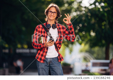 Everything is fine, hand gesture. Young student is having a walk in the town Everything is fine, hand gesture. Young student is having a walk in the town 139166246