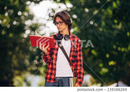 Red book, reading it. Young student is having a walk in the town Red book, reading it. Young student is having a walk in the town 139166269
