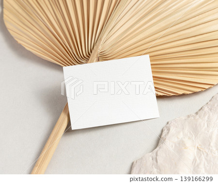 Blank card mockup with dried palm leaf on beige stone top view, boho wedding stationery Blank card mockup with dried palm leaf on beige stone top view, boho wedding stationery 139166299