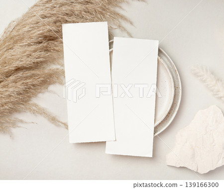 Blank vertical cards mockup on pampas grass and beige stone top view, boho wedding stationery 139166300