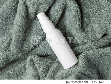 White spray cosmetic bottle mockup on sage green bath towel top view. Unbranded blank packaging White spray cosmetic bottle mockup on sage green bath towel top view. Unbranded blank packaging 139166308