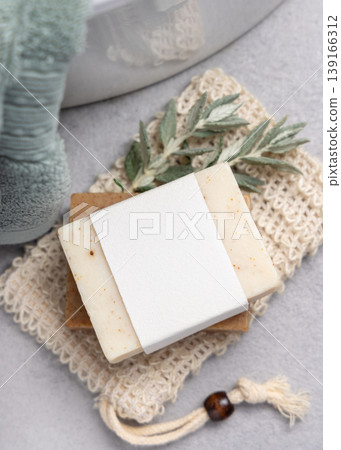 Beige solid soap bar with blank paper label mockup near with leaves and light green bath towel Beige solid soap bar with blank paper label mockup near with leaves and light green bath towel 139166312