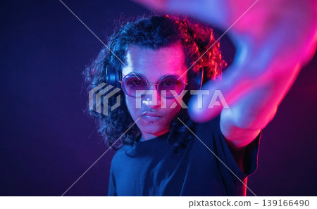 Performance of DJ, in headphones. Guy is indoors at night with neon lighting 139166490