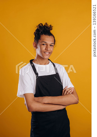 Barista is in apron. Young guy is against yellow background Barista is in apron. Young guy is against yellow background 139166521