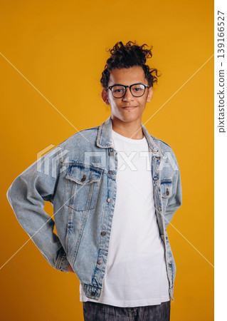 In jean jacket. Young guy is against yellow background In jean jacket. Young guy is against yellow background 139166527