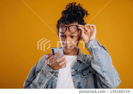 Internet conception, using smartphone. Young guy is against yellow background Internet conception, using smartphone. Young guy is against yellow background 139166534