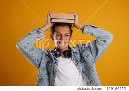 Ready to learn, with books. Young guy is against yellow background 139166555