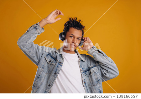 Music lover, in headphones. Young guy is against yellow background Music lover, in headphones. Young guy is against yellow background 139166557