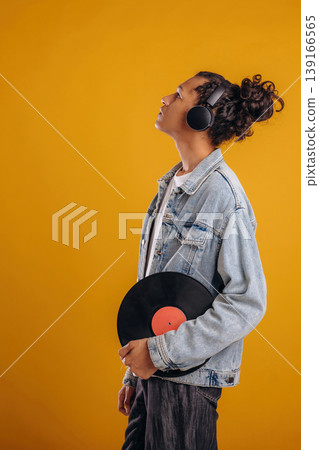 Retro vinyl record in hand. Young guy is against yellow background Retro vinyl record in hand. Young guy is against yellow background 139166565