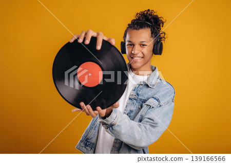 Retro vinyl record in hands. Young guy is against yellow background Retro vinyl record in hands. Young guy is against yellow background 139166566