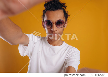 Selfie time, posing. Young guy is against yellow background Selfie time, posing. Young guy is against yellow background 139166585