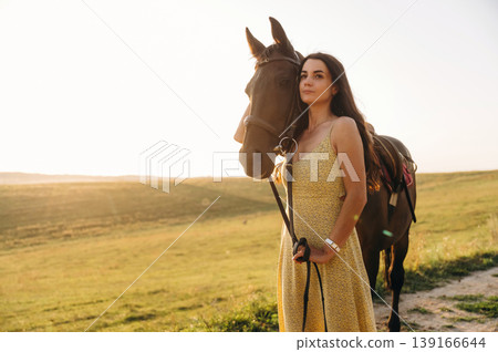Pretty woman is having a walk with horse outdoors Pretty woman is having a walk with horse outdoors 139166644