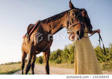 Pretty woman is having a walk with horse outdoors Pretty woman is having a walk with horse outdoors 139166645