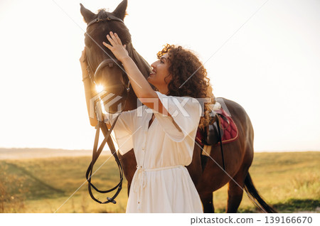 White sky, against it. Woman in dress is with horse on the countryside field 139166670
