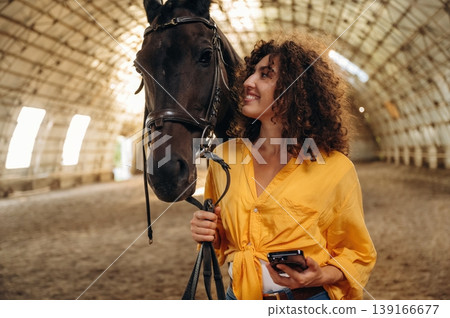 Love and care conception. Beautiful young woman is with horse in hangar Love and care conception. Beautiful young woman is with horse in hangar 139166677