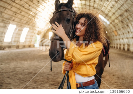 Smiling, having fun. Beautiful young woman is with horse in hangar Smiling, having fun. Beautiful young woman is with horse in hangar 139166690