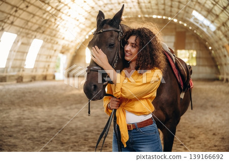 Taking care of animal. Beautiful young woman is with horse in hangar Taking care of animal. Beautiful young woman is with horse in hangar 139166692