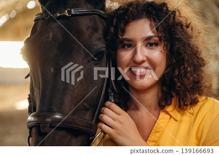 Smiling, having fun. Beautiful young woman is with horse in hangar Smiling, having fun. Beautiful young woman is with horse in hangar 139166693