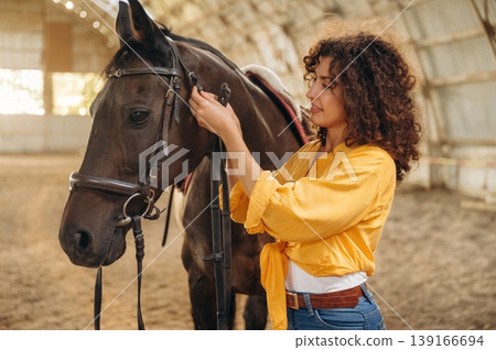 Taking care of animal. Beautiful young woman is with horse in hangar Taking care of animal. Beautiful young woman is with horse in hangar 139166694