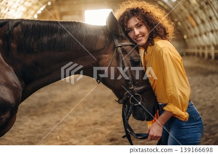 Love and care conception. Beautiful young woman is with horse in hangar Love and care conception. Beautiful young woman is with horse in hangar 139166698