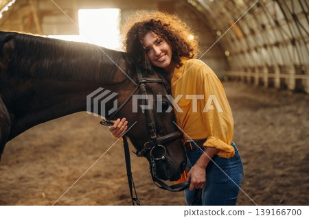 Love and care conception. Beautiful young woman is with horse in hangar Love and care conception. Beautiful young woman is with horse in hangar 139166700