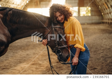 Feeling good, taking care of animal. Beautiful young woman is with horse in hangar Feeling good, taking care of animal. Beautiful young woman is with horse in hangar 139166701