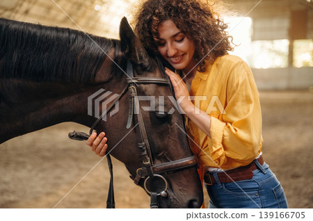 Embracing the animal. Beautiful young woman is with horse in hangar Embracing the animal. Beautiful young woman is with horse in hangar 139166705