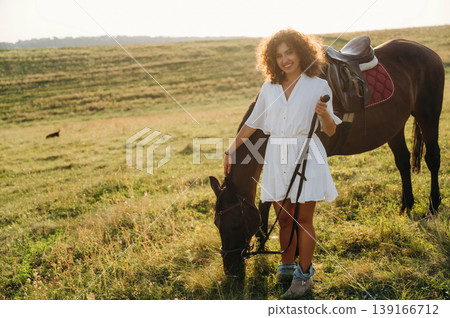 Non urban scene. Woman in white dress is with horse on the countryside field Non urban scene. Woman in white dress is with horse on the countryside field 139166712