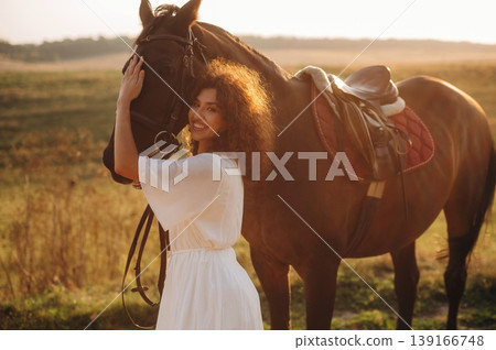 Woman in white dress is with horse on the countryside field Woman in white dress is with horse on the countryside field 139166748